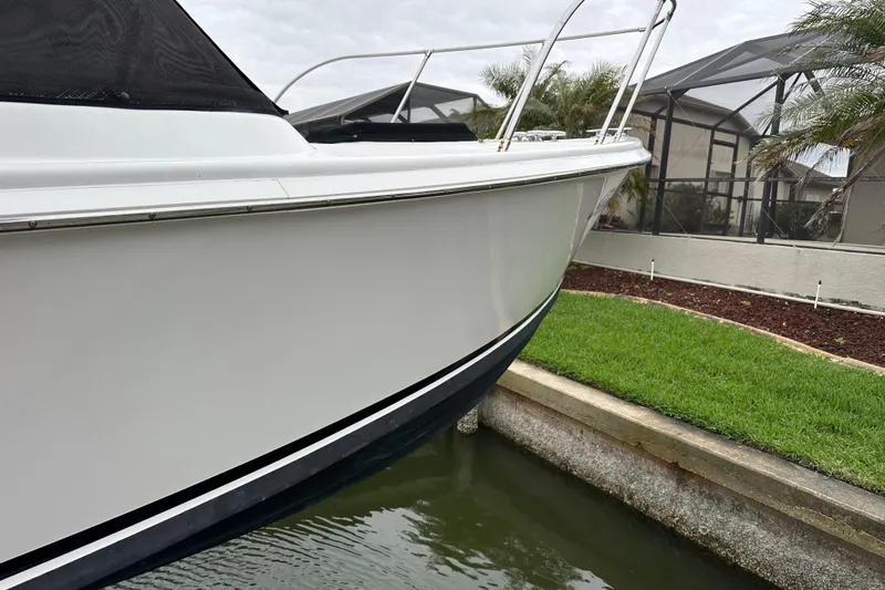 Slide: The Image of 1975 Bertram 31 boat docked near a grassy area, showcasing sleek white hull. - 9