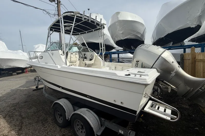 The Image of 2002 Wellcraft 22 Coastal Walkaround O/B boat on trailer, parked outdoors. - 1