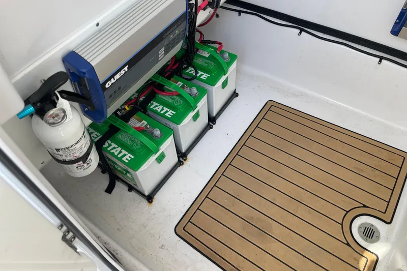 Slide: The Image of 2024 Sportsman Masters 247 Bay Boat battery compartment with charger and fire extinguisher. - 26