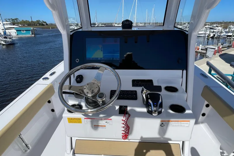 Slide: The Image of 2024 Sportsman Masters 247 Bay Boat helm with steering wheel and navigation display. - 6