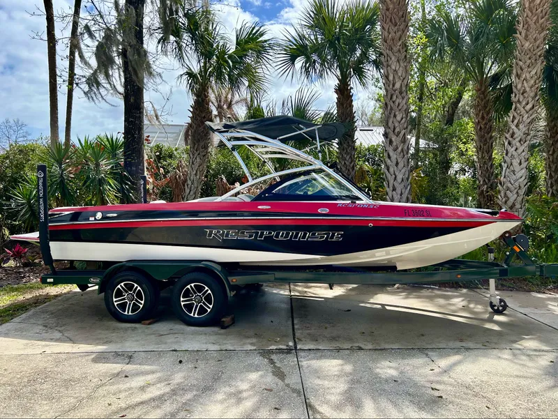 The Image of 2012 Malibu Response TXi boat on trailer, surrounded by palm trees. - 1