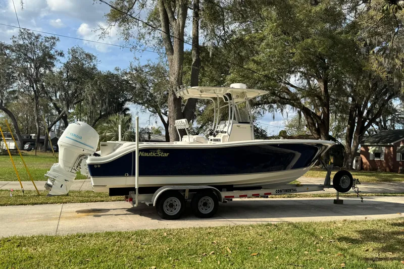 The Image of 2012 NauticStar 2500XS Offshore boat on trailer, parked outdoors. - 0