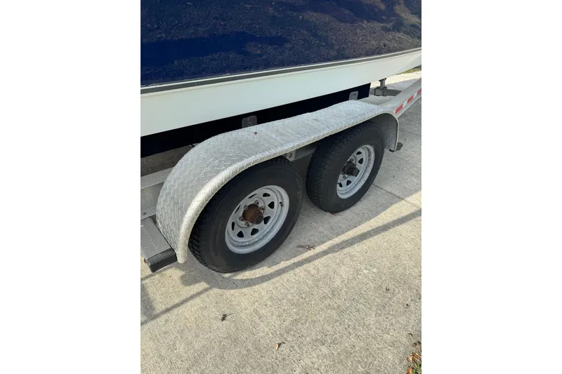 Slide: The Image of Trailer wheels of a 2012 NauticStar 2500XS Offshore boat on pavement. - 12