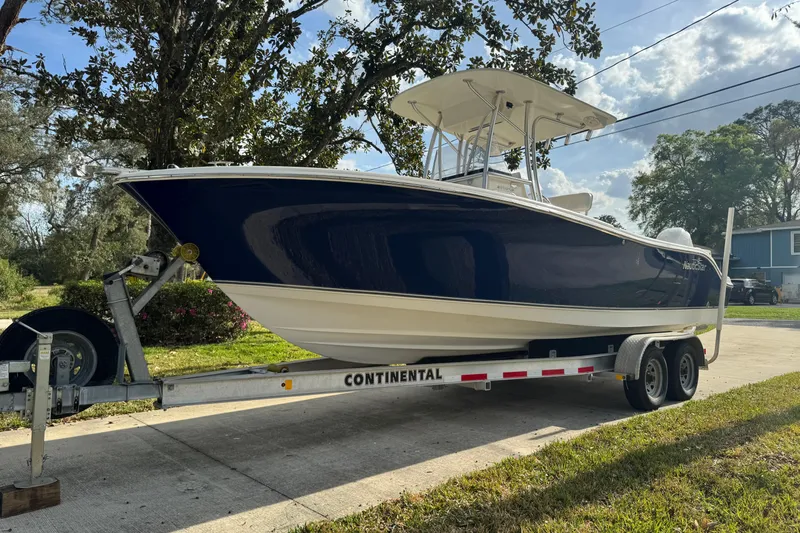 Slide: The Image of 2012 NauticStar 2500XS Offshore boat on trailer, parked outdoors under a clear sky. - 3