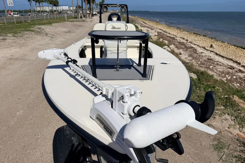 Slide: The Image of 2021 Maverick 18 HPX-V boat with trolling motor, parked near a coastal shoreline. - 13
