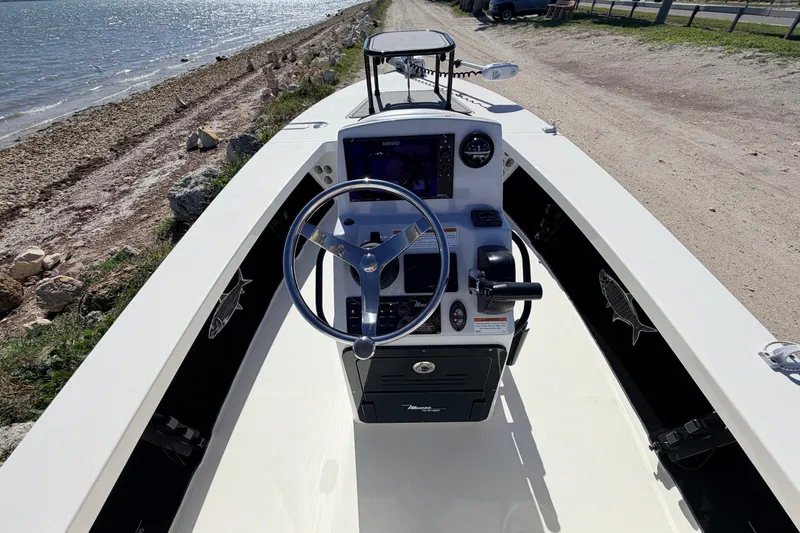 Slide: The Image of 2021 Maverick 18 HPX-V boat interior with steering wheel and control panel by the shoreline. - 29