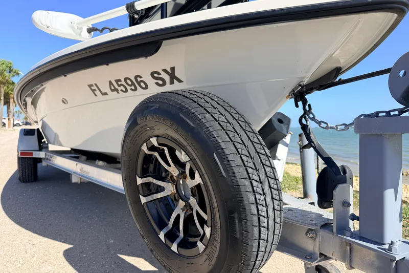 Slide: The Image of 2021 Maverick 18 HPX-V boat on trailer by the shore, showcasing tire and hull details. - 7