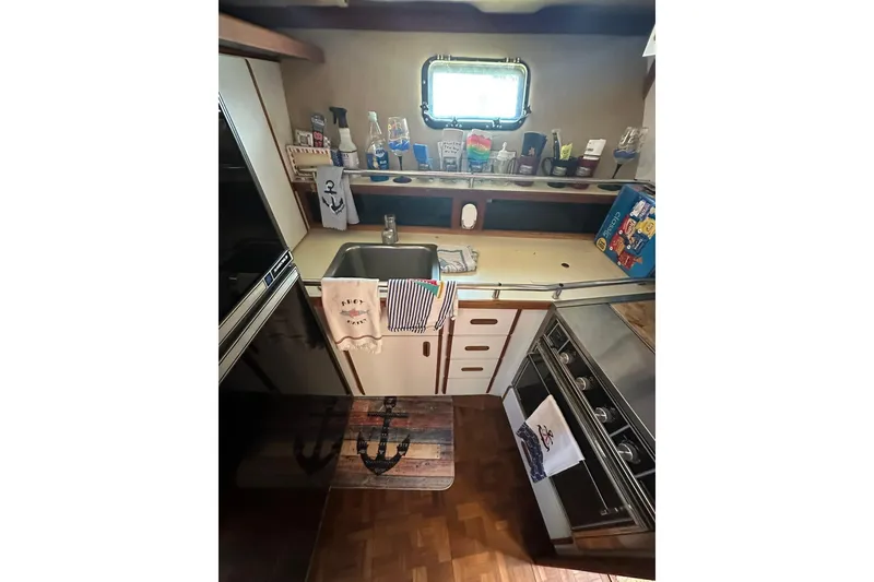 Slide: The Image of 1985 Carver 3207 Aft Cabin Motor Yacht kitchen with sink, stove, and nautical decor. - 12