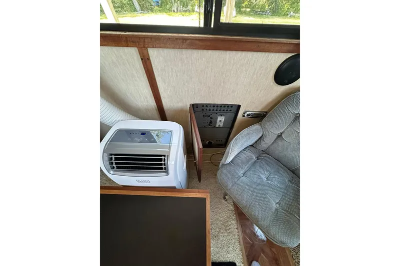 Slide: The Image of Interior of 1985 Carver 3207 Aft Cabin Yacht with portable air conditioner and cushioned chair. - 25