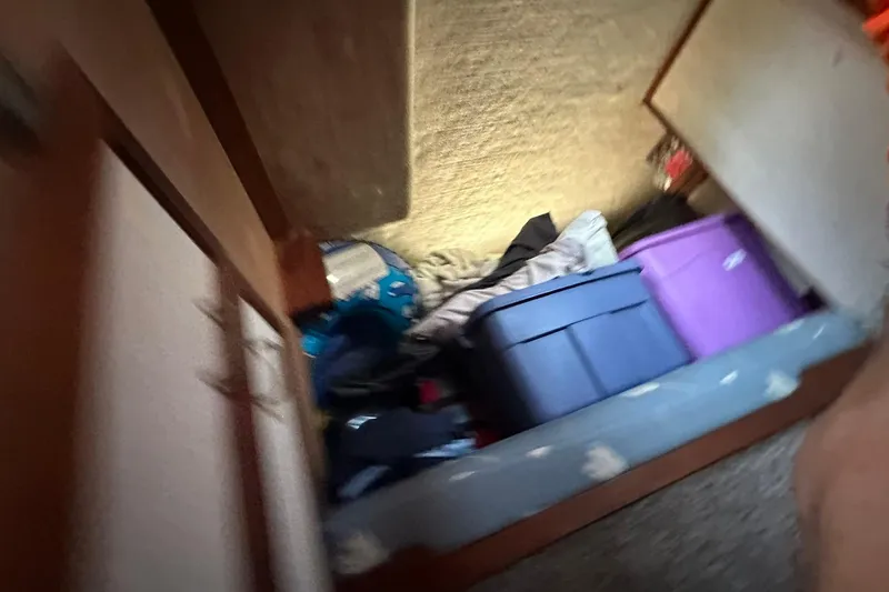 Slide: The Image of Storage area inside 1985 Carver 3207 Aft Cabin Motor Yacht with bins and clothing. - 32