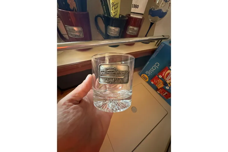 Slide: The Image of Hand holding a glass with a yacht emblem, surrounded by mugs and snacks. - 33