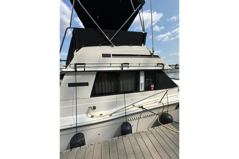 Slide: The Image of 1985 Carver 3207 Aft Cabin Motor Yacht docked, featuring black canopy and white hull. - 4