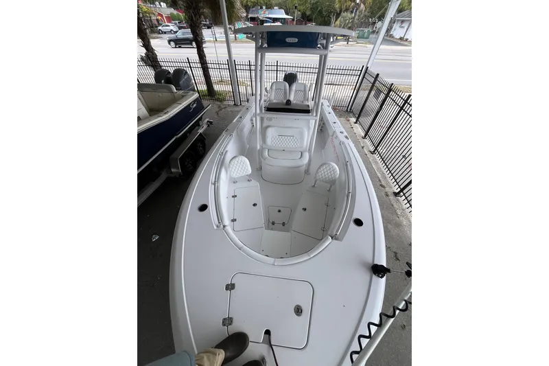 Slide: The Image of 2024 Sportsman Open 212 Center Console boat, white interior, parked near a fence. - 10