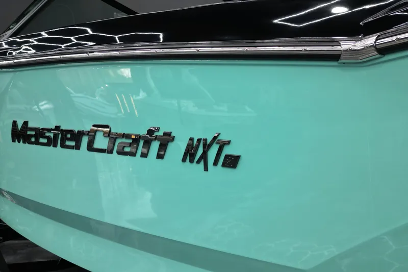 Slide: The Image of 2024 MasterCraft NXT21 boat with sleek turquoise and black design. - 12