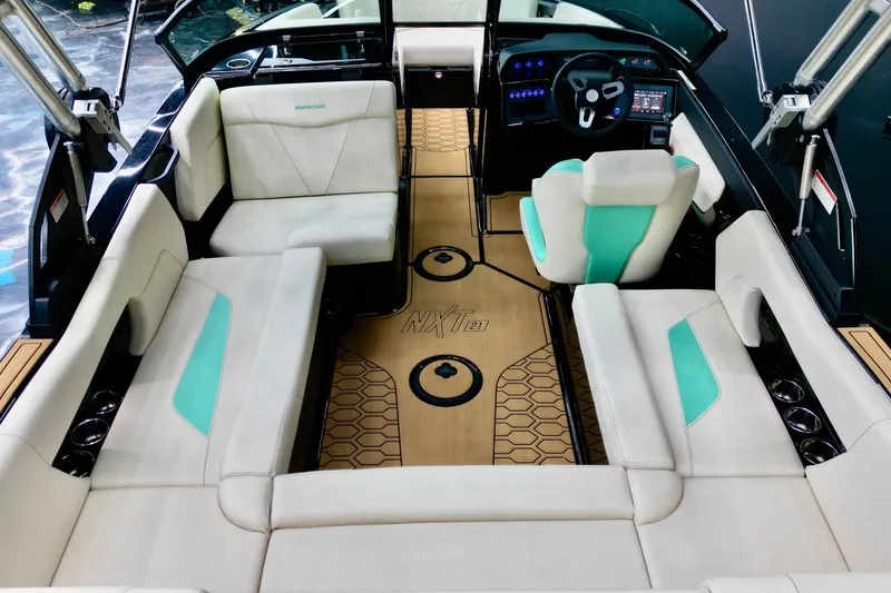Slide: The Image of 2024 MasterCraft NXT21 boat interior with white and teal seating, modern dashboard, and wood flooring. - 8
