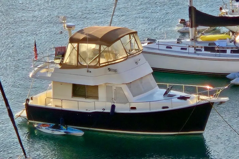 The Image of 2008 Mainship 34 Trawler yacht docked in a marina, surrounded by calm water. - 0