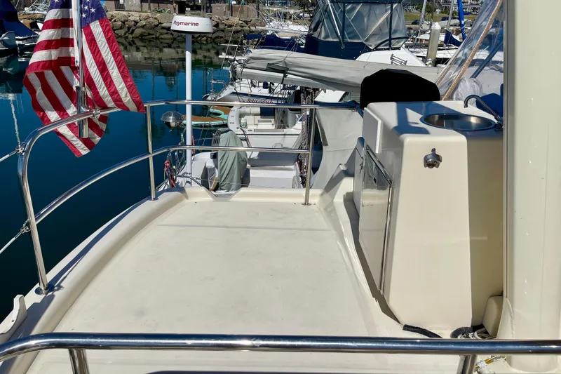 Slide: The Image of 2008 Mainship 34 Trawler deck with American flag and marina view. - 26