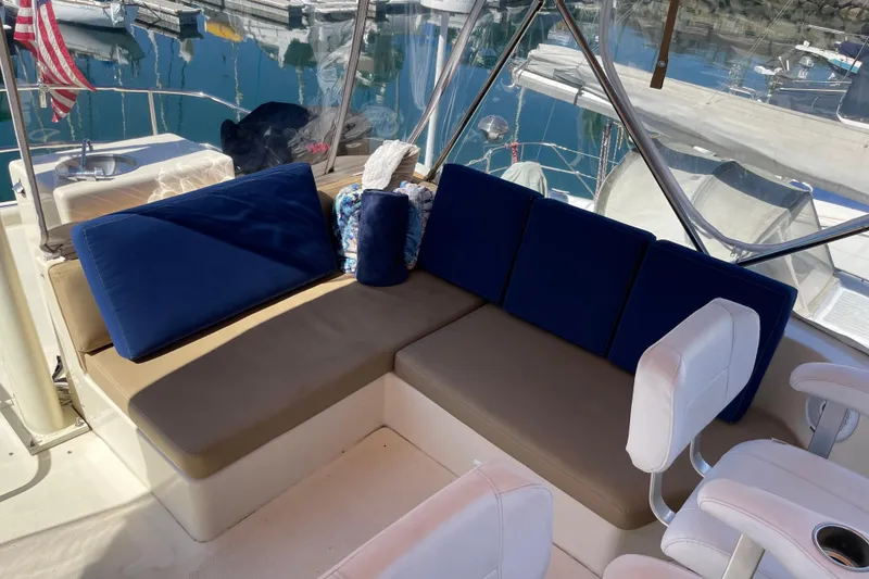 Slide: The Image of 2008 Mainship 34 Trawler interior with blue cushions and white seating in marina setting. - 29