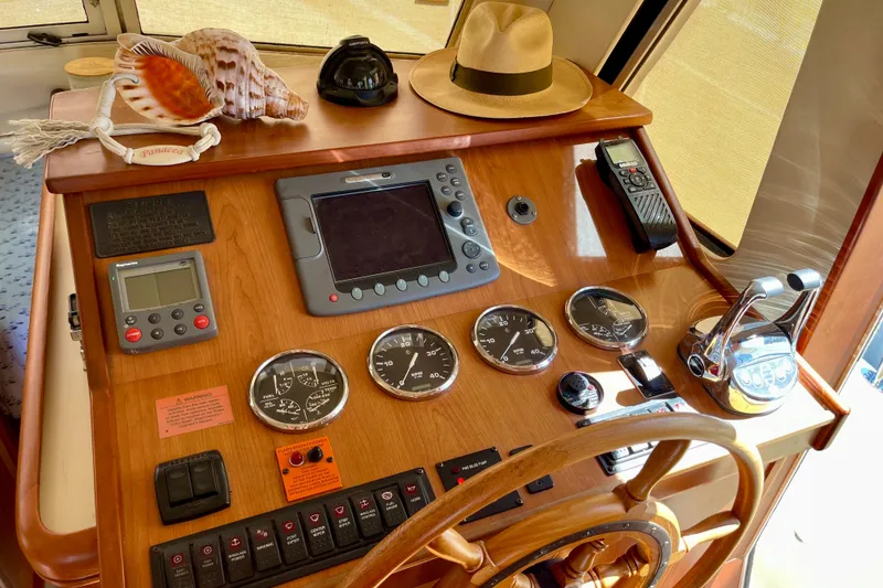 Slide: The Image of 2008 Mainship 34 Trawler helm with navigation instruments, gauges, and decorative seashells. - 38