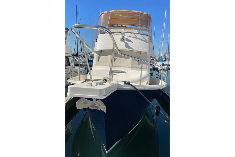 Slide: The Image of 2008 Mainship 34 Trawler docked in marina, front view with clear blue sky. - 4