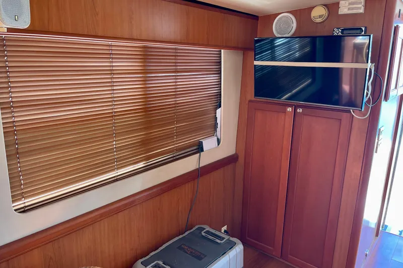 Slide: The Image of Interior of 2008 Mainship 34 Trawler with wooden cabinets and a mounted TV. - 42