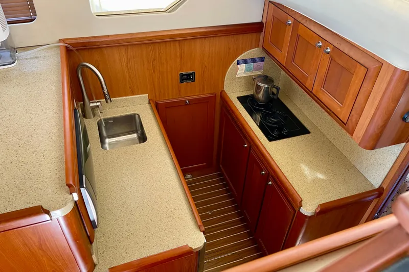 Slide: The Image of 2008 Mainship 34 Trawler kitchen with wood cabinets, sink, and stovetop. - 45