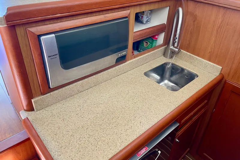 Slide: The Image of 2008 Mainship 34 Trawler galley with microwave, sink, and wooden cabinetry. - 47