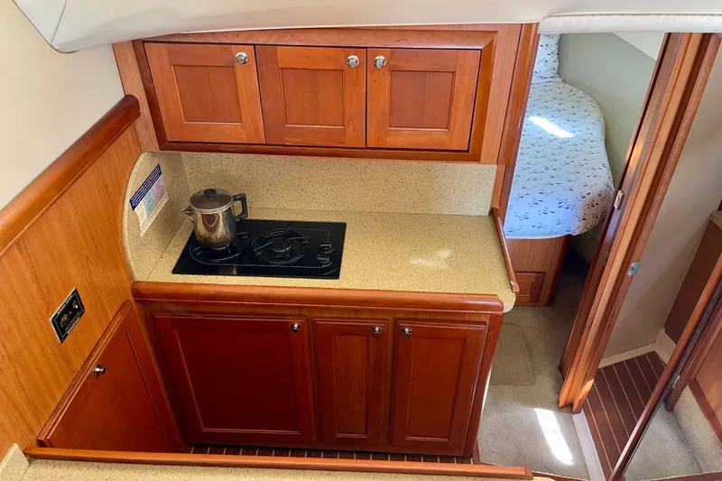 Slide: The Image of 2008 Mainship 34 Trawler interior with wooden cabinetry and compact kitchen area. - 48