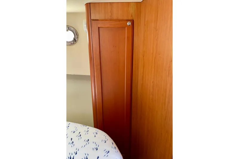 Slide: The Image of Wooden interior of 2008 Mainship 34 Trawler, featuring a sleek cabinet and porthole. - 53