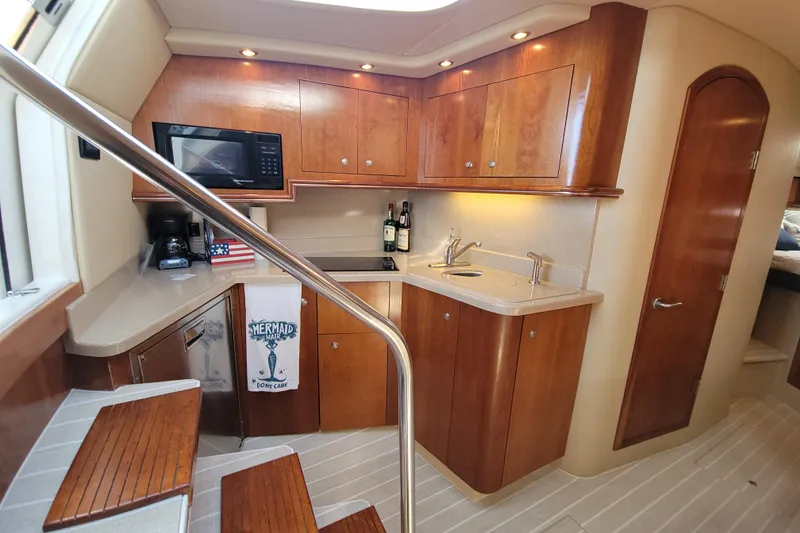 Slide: The Image of 2005 Cruisers Yachts 340 Express interior kitchen with wood cabinets and modern appliances. - 10