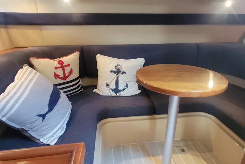 Slide: The Image of Interior of 2005 Cruisers Yachts 340 Express with nautical-themed cushions and wooden table. - 14