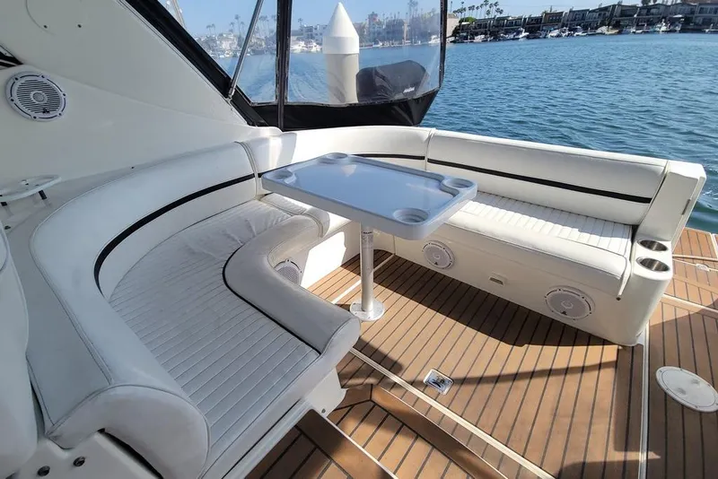 Slide: The Image of 2005 Cruisers Yachts 340 Express interior with white seating and table, overlooking marina. - 16