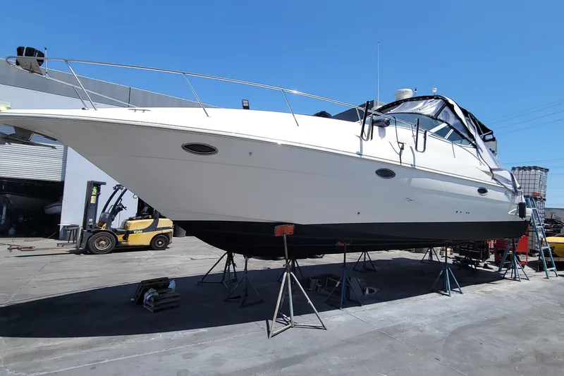 Slide: The Image of 2005 Cruisers Yachts 340 Express on stands in a boatyard under clear blue sky. - 21