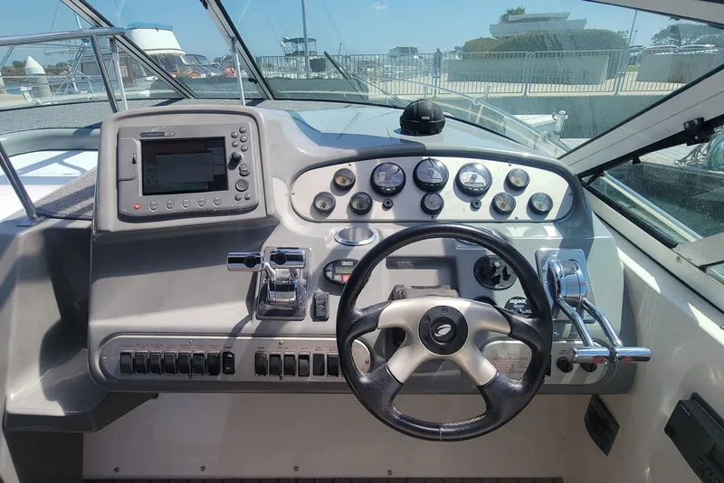 Slide: The Image of Cockpit of 2005 Cruisers Yachts 340 Express, featuring steering wheel and control panel. - 4