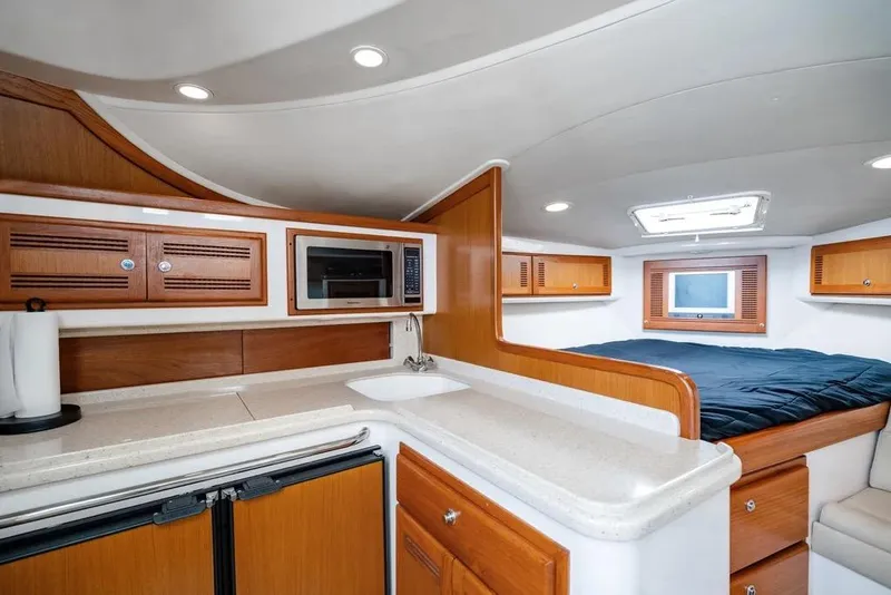 Slide: The Image of 2005 Cabo 35 Express yacht interior with kitchenette, bed, and storage cabinets. - 18