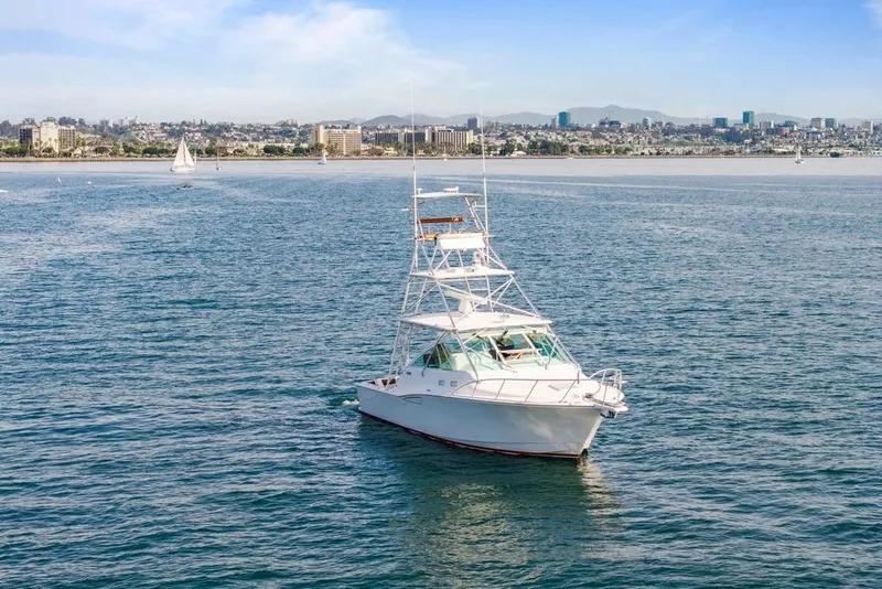 Slide: The Image of 2003 Cabo 35 Express yacht cruising on a sunny day near a coastal cityscape. - 5