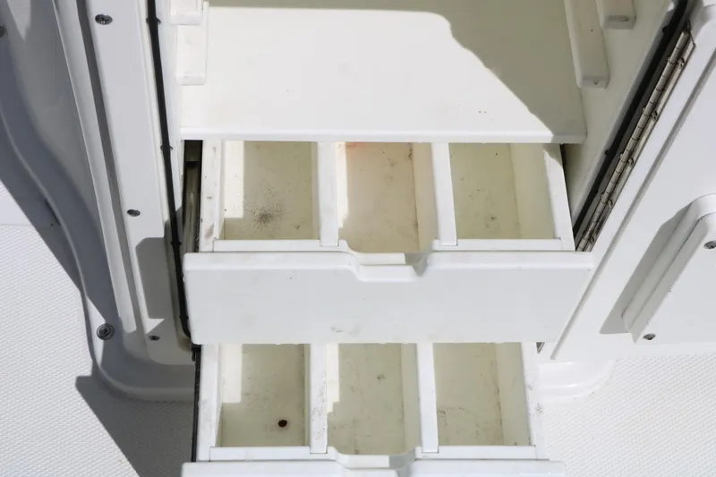 Slide: The Image of Storage compartments on a 2016 Sea Hunt BX 22 BR boat, featuring white pull-out drawers. - 56