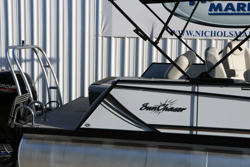Slide: The Image of 2024 Sun Chaser Geneva SB DH pontoon boat with Mercury engine, docked near a metal building. - 14