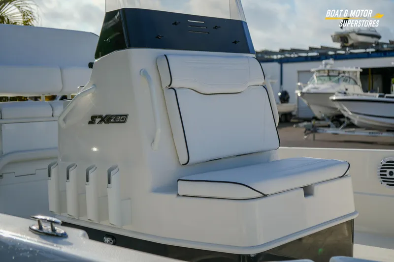 Slide: The Image of 2026 Skeeter SX230 boat interior with cushioned seating and rod holders at a dealership. - 12