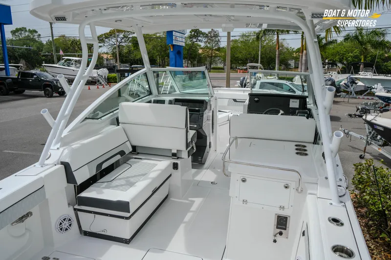 Slide: The Image of 2026 Blackfin 272 DC boat interior with seating and helm, displayed at a dealership. - 17