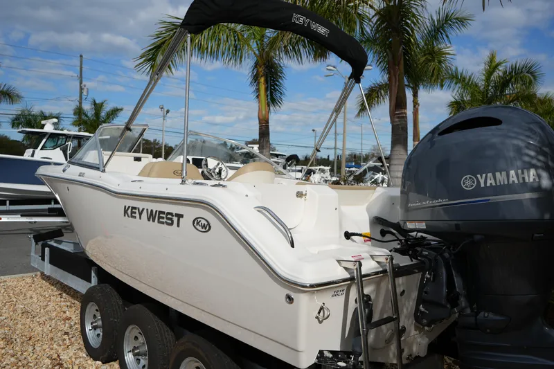 Slide: The Image of 2020 Key West 203 DFS boat with Yamaha engine, parked on a trailer, surrounded by palm trees. - 13