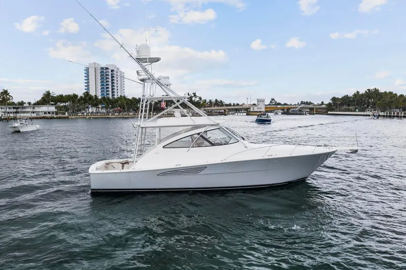 Slide: The Image of 2018 Viking 44 Express yacht cruising on a scenic waterway with buildings in the background. - 29