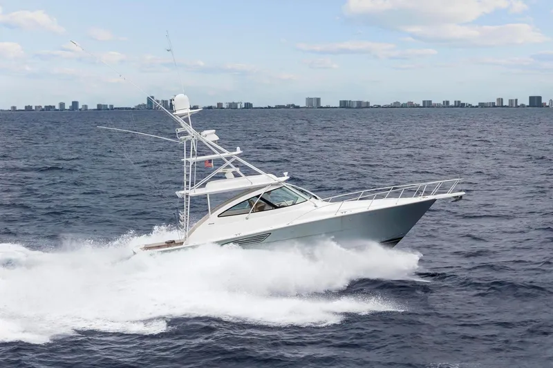 Slide: The Image of 2018 Viking 44 Express yacht cruising on open ocean with city skyline in background. - 43