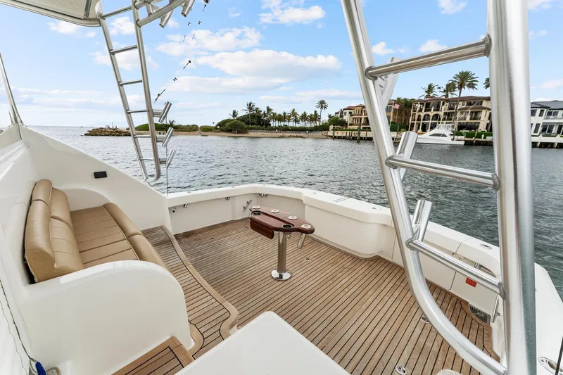 Slide: The Image of 2018 Viking 44 Express yacht deck with seating, ladder, and scenic waterfront view. - 49