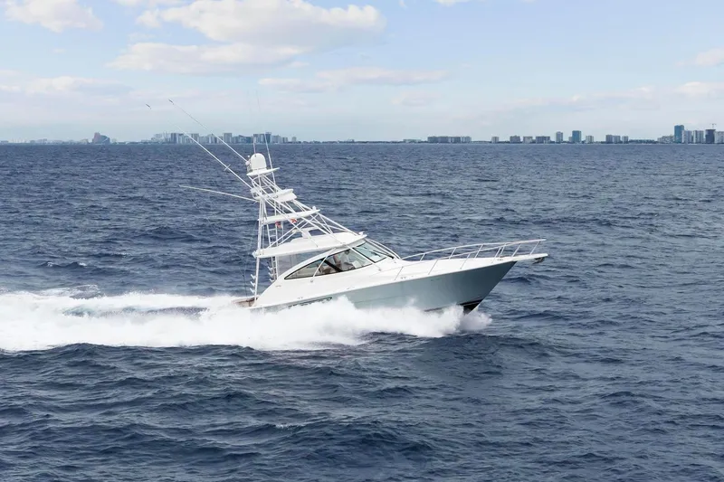 Slide: The Image of 2018 Viking 44 Express yacht cruising on open ocean with city skyline in background. - 6