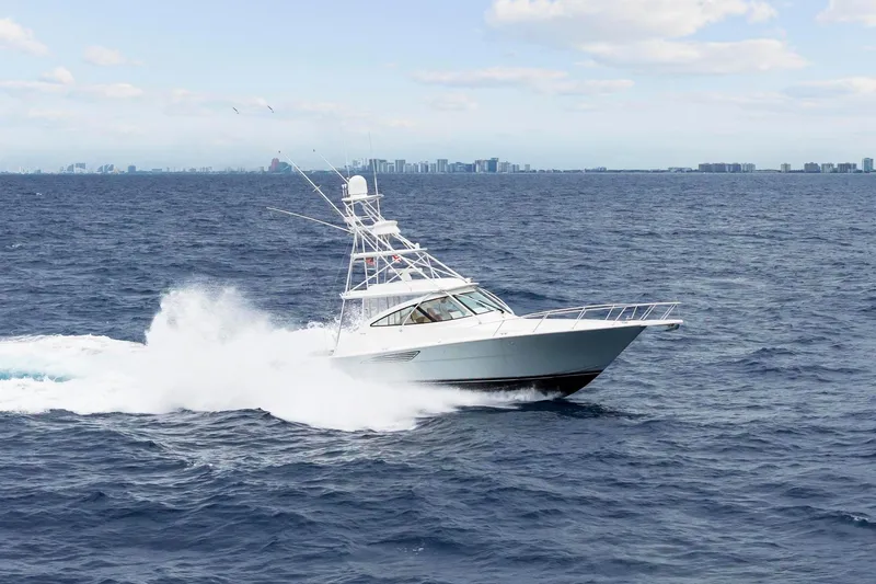 Slide: The Image of 2018 Viking 44 Express yacht cruising on open ocean with city skyline in background. - 7