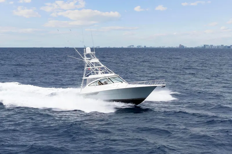 Slide: The Image of 2018 Viking 44 Express yacht cruising on open ocean with city skyline in background. - 8
