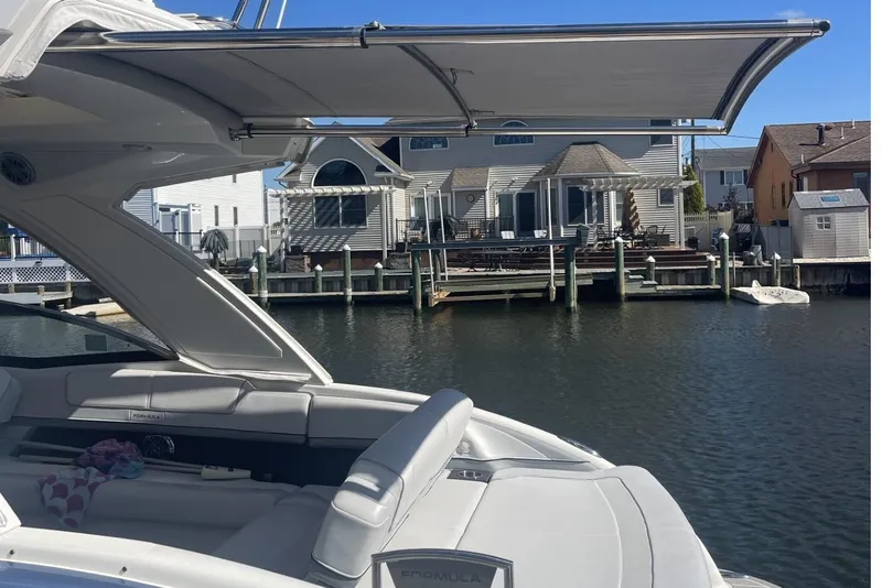 Slide: The Image of 2020 Formula 310 Bowrider OB docked near waterfront homes, featuring a sleek design and spacious seating. - 2