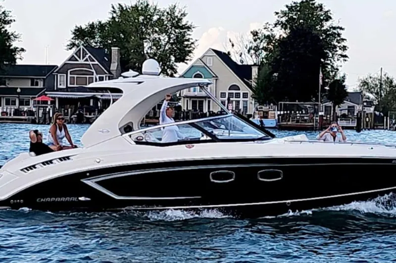 The Image of 2014 Chaparral 327 SSX boat cruising on a lake near waterfront homes. - 0