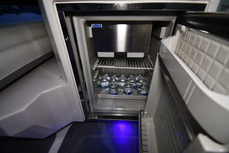 Slide: The Image of Mini fridge stocked with water bottles inside a 2014 Chaparral 327 SSX boat. - 16